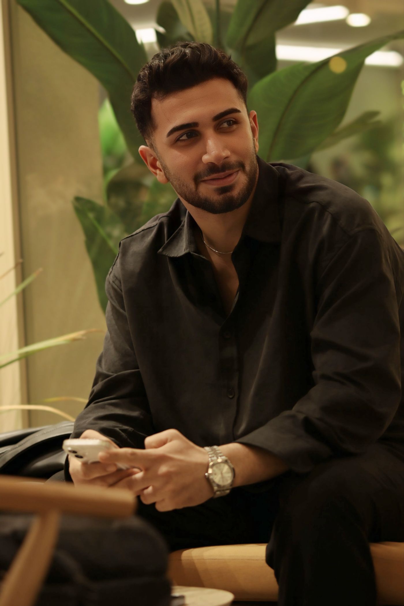 A man at a cafรฉ smiling at his phone after paying